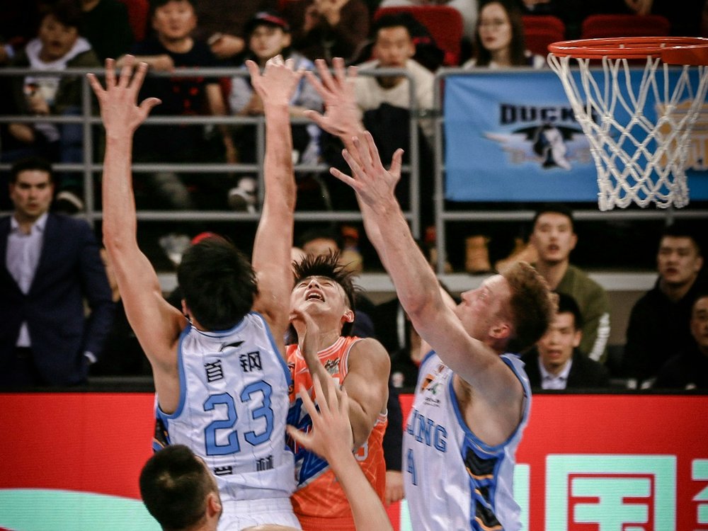 Basketball teams contesting the ball beneath the hoop